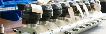 Un șir de contoare de gaz cu capete indicatoare negre și etichete de hârtie, aliniate pe un banc, cu cutii albastre de depozitare în spate.
