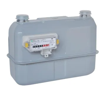 Un contor de gaz gri deschis, cu două racorduri de țeavă acoperite cu capace în partea de sus și o fereastră frontală a mecanismului indicator, în care se văd rolele cu cifre, între două urechi laterale galbene.