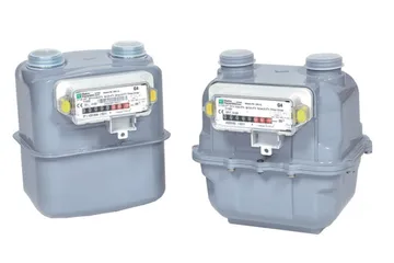 Două contoare de gaz gri, unul lângă altul, fiecare cu două racorduri de țeavă în partea de sus și o fereastră frontală în care se vede un șir de cifre, între două urechi laterale galbene.